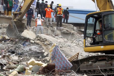 Rescue workers watch as an excavator removes rubble at the site of a collapsed building at the Synagogue Church of All Nations in the Ikotun-Egbe neighbourhood of Nigeria's commercial capital Lagos, September 17, 2014. REUTERS/Akintunde Akinleye