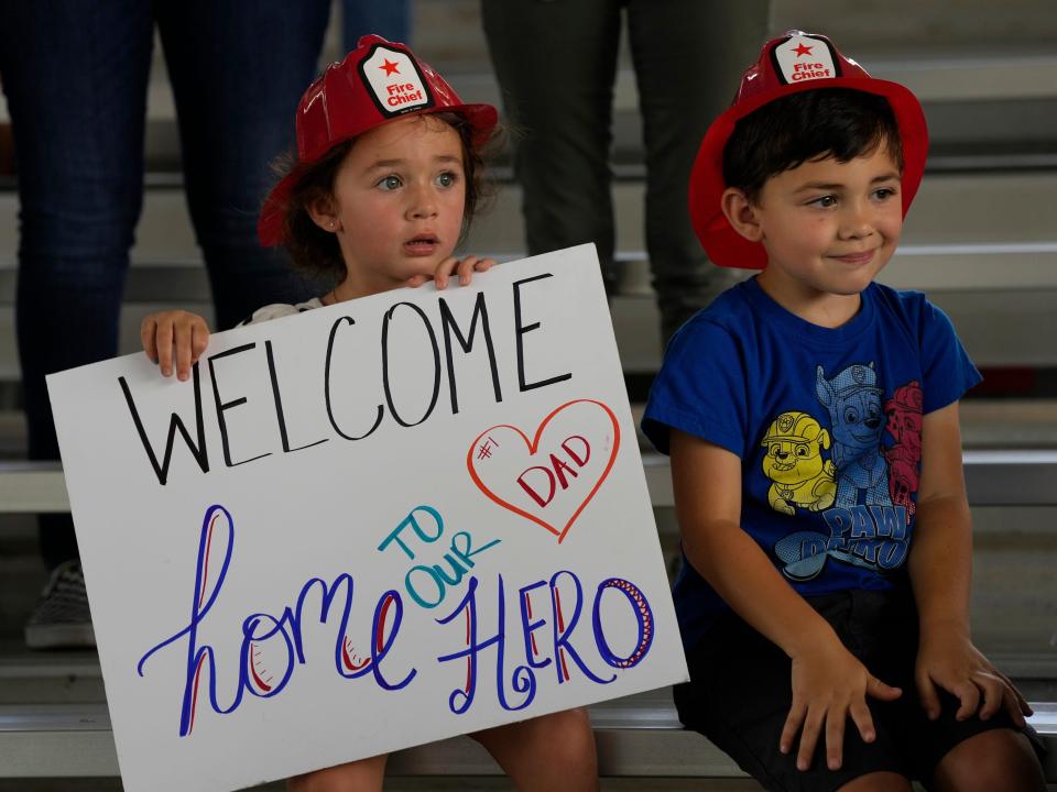 Two children hold a sign that says "Welcome home to our hero."