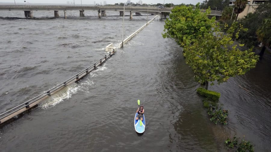 Flood waters pushed by Hurricane Idalia pour over the sea wall along Old Tampa Bay as paddle boarder Zeke Pierce, of Tampa, rides Wednesday, Aug. 30, 2023, in Tampa, Fla. (AP Photo/Chris O’Meara)