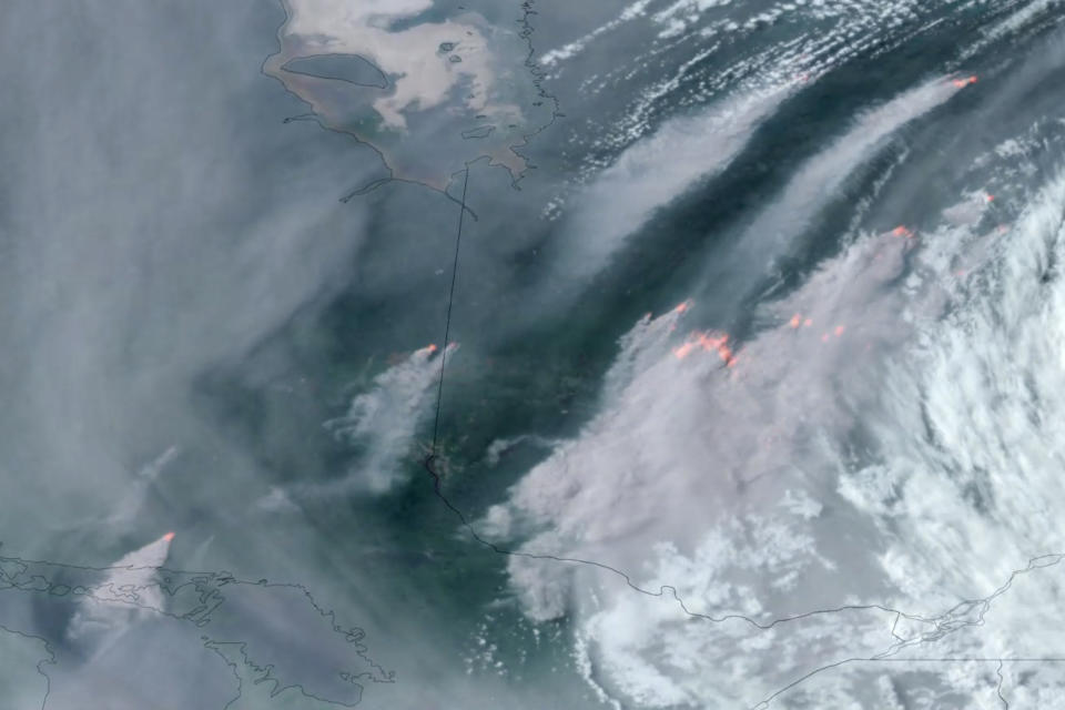 In this GOES-16 GeoColor and fire temperature satellite image taken Tuesday, June 6, 2023 at 6:40 p.m. EDT and provided by CIRA/NOAA, smoke from wildfires burning in the Canadian Provinces of Quebec, right, and Ontario, left, drift southward. (CIRA/NOAA via AP)