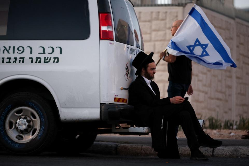 A man carries an Israeli flag next to an ultra-Orthodox Jew as protesters gather for a demonstration against Israeli Prime Minister Benjamin Netanyahu's government, near the Knesset, the Israeli parliament, in Jerusalem June 17, 2024. REUTERS/Marko Djurica