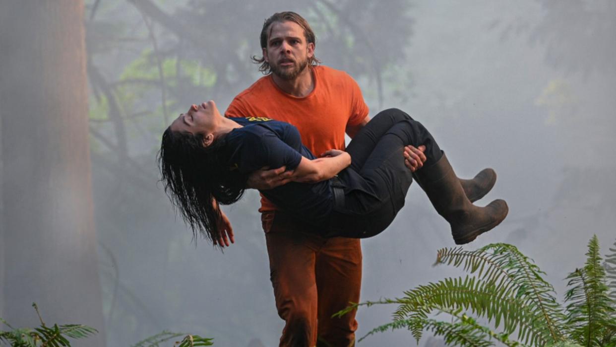  Max Thieriot running with Stephanie Arcila in her arms. 