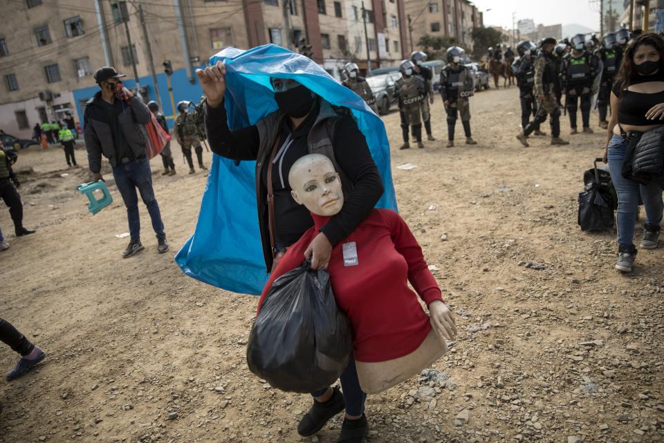 A street vendor walks away with her mannequin during a police operation to evict a group of street vendors who came out to sell their products, ignoring lockdown measures to curb the spread of the new coronavirus, in La Victoria district, in Lima, Peru, Tuesday, June 16, 2020. (AP Photo/Rodrigo Abd)