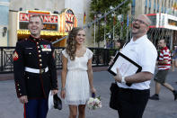 LAS VEGAS - OCTOBER 6: (L-R) Trevor Felten of Indiana and Jessica Gallatin of Texas joke with the Rev. Andy Gonzalez of the Las Vegas Wedding Wagon before their wedding outside the New York-New York Hotel & Casino on the Las Vegas Strip on October 6, 2012 in Las Vegas, Nevada. For USD 99, ordained ministers will drive a van with an altar to any location in and around Las Vegas and perform a legal wedding, vow renewal or commitment ceremony in about 10 minutes. The fee includes wedding photos but not a marriage license. Couples can either get hitched at the Wedding Wagon's walk-up window or at iconic areas including the Welcome to Fabulous Las Vegas sign, the fountains at the Bellagio, the Hoover Dam and pedestrian bridges overlooking the Las Vegas Strip. (Photo by Isaac Brekken/Getty Images)