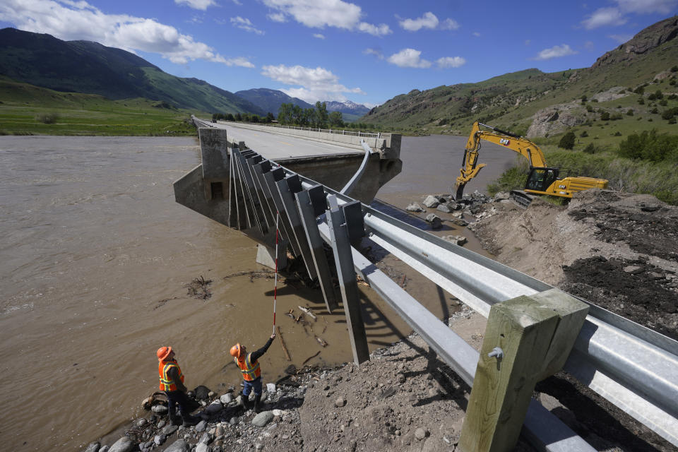 Highway workers inspect a washed out bridge along the Yellowstone River Wednesday, June 15, 2022, near Gardiner, Mont. (AP Photo/Rick Bowmer)