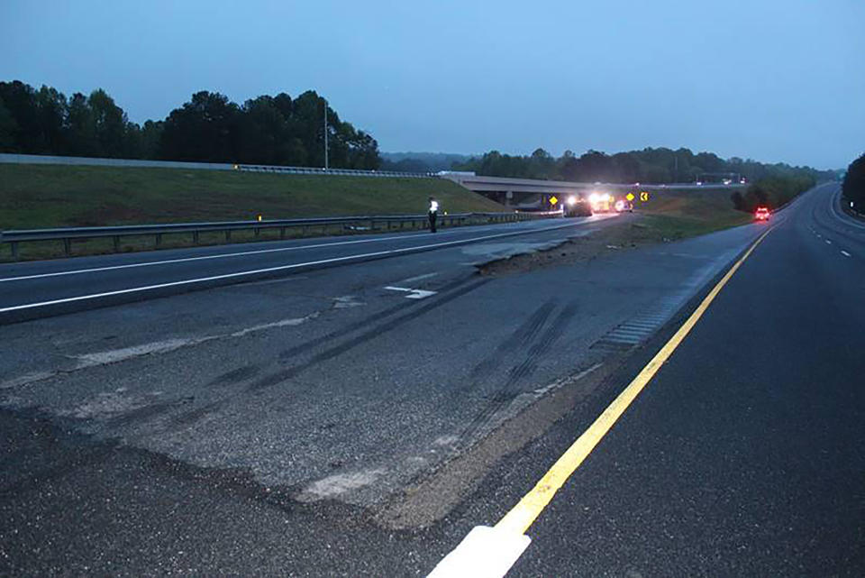 This photo provided by the Gwinnett County Police Department shows tire marks on the pavement, front, near the scene of a deadly crash in Gwinnett County, Ga., Saturday, April 24. 2021. Police in Georgia say multiple people died and several others were hurt in the interstate crash. Gwinnett County police say the crash left a passenger van engulfed in flames and rolled on its side Saturday evening. (Gwinnett County Police Department via AP)