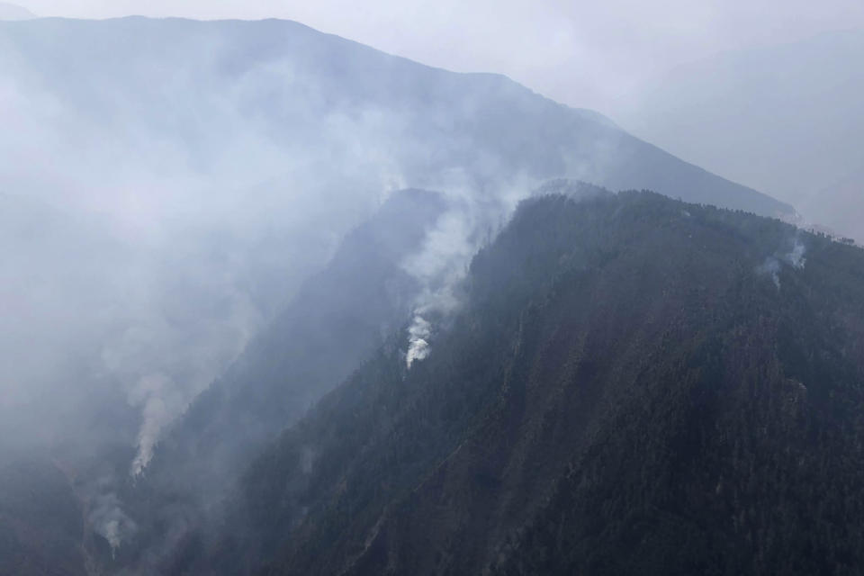 In this aerial photo released by Xinhua News Agency, smoke can be seen from a forest fire in Yalongjiang township of Muli County, Liangshan Yi Autonomous Prefecture in southwestern China's Sichuan Province on Monday, April 1, 2019. The fire high in the mountains of western China's Sichuan province has killed over two dozen firefighters and others, the government said Monday. (Lin Jiping/Xinhua via AP)