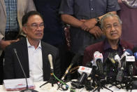 In this Feb. 22, 2020, photo, Malaysian Prime Minister Mahathir Mohamad, right, talks to media next to his successor Anwar Ibrahim in Putrajaya, Malaysia. Political tension is building in Malaysia amid talks that Mahathir will pull his party out of the ruling alliance and team up with opposition parties to form a new government in a major political upheaval. It will thwart his named successor Anwar Ibrahim from taking over.(AP Photo/Vincent Thian)