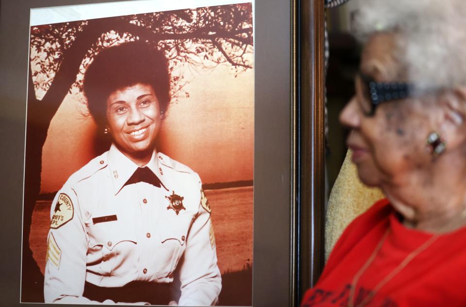 Ora Jackson, 99, sits in the family living room of their home next to a photo taken during her time working with the Shelby County Sheriff's Office on Friday, June, 11, 2021.