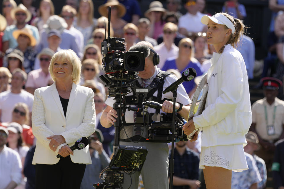 Kazakhstan's Elena Rybakina is interviewed by Sue Barker as he holds the trophy as she celebrates after beating Tunisia's Ons Jabeur to win the final of the women's singles on day thirteen of the Wimbledon tennis championships in London, Saturday, July 9, 2022. (AP Photo/Kirsty Wigglesworth)