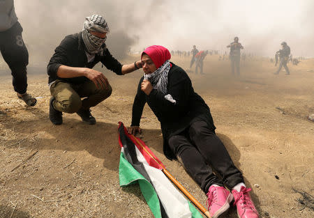 A woman demonstrator reacts to tear gas fired by Israeli troops during clashes at a protest at the Israel-Gaza border where Palestinians demand the right to return to their homeland, east of Gaza City April 20, 2018. REUTERS/Mohammed Salem