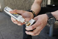In this Monday, June 17, 2019, photo, Jacky Chan, 23, refills his electronic cigarette with vaping liquid in San Francisco. San Francisco supervisors are considering whether to move the city toward becoming the first in the United States to ban all sales of electronic cigarettes in an effort to crack down on youth vaping. The plan would ban the sale and distribution of e-cigarettes, as well as prohibit e-cigarette manufacturing on city property. (AP Photo/Samantha Maldonado)