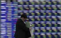 A man walks past a stock quotation board outside a brokerage in Tokyo December 4, 2013. REUTERS/Toru Hanai