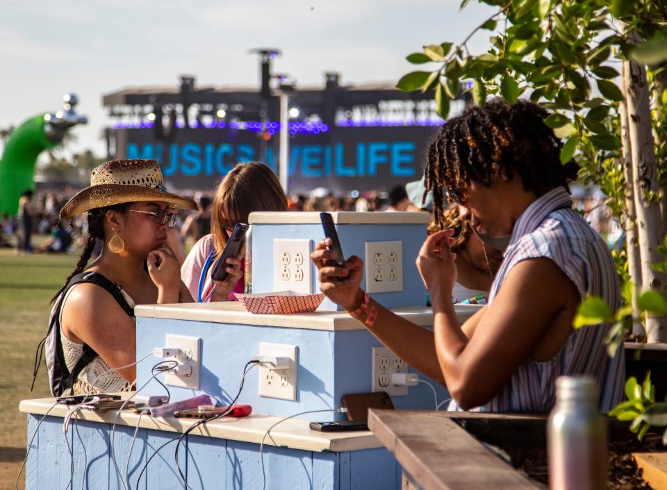Festivalgoers charge their devices at one of the charging stations on the grounds at the Coachella Valley Music and Arts Festival at the Empire Polo Club in Indio, Calif., Sunday, April 16, 2023.