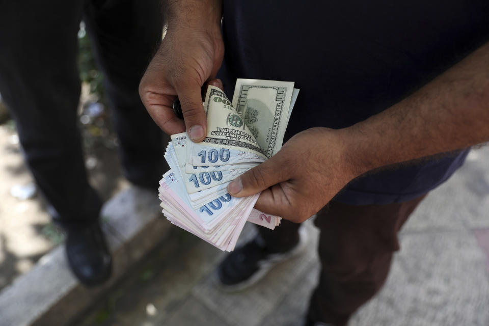 A street money exchanger poses for a photo without showing his face as he counts foreign banknotes in Ferdowsi street, Tehran's go-to venue for foreign currency exchange, Iran, Sunday, June 12, 2022. Iran's currency Sunday dropped to its lowest value ever as talks to revive the country's tattered nuclear deal with world powers remained deadlocked. (AP Photo/Vahid Salemi)