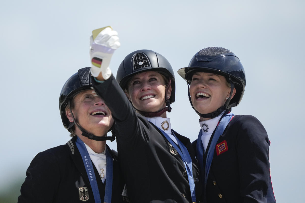 From left: Isabell Werth and Jessica von Bredow-Werndl, of Germany, and Charlotte Fry, of Britain,  take a selfie to celebrate their silver, gold and bronze medals at the dressage individual Grand Prix freestyle competition at the Paris Olympics on Sunday. 