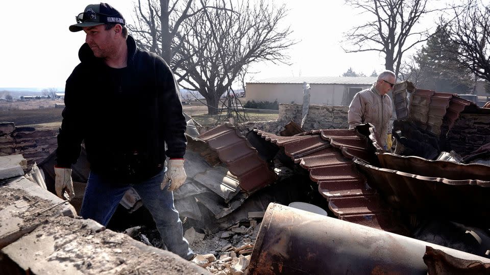 Mason Holloway and Hugh Lively sift through the remains of a relative's home destroyed by the Smokehouse Creek Fire in Canadian, Texas, on Wednesday. - Nick Oxford/Reuters
