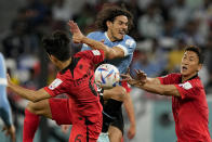 Uruguay's Edinson Cavani, center, fights for the ball with South Korea's Hwang In-beom, left, and Jung Woo-young during the World Cup group H soccer match between Uruguay and South Korea, at the Education City Stadium in Al Rayyan , Qatar, Thursday, Nov. 24, 2022. (AP Photo/Martin Meissner)