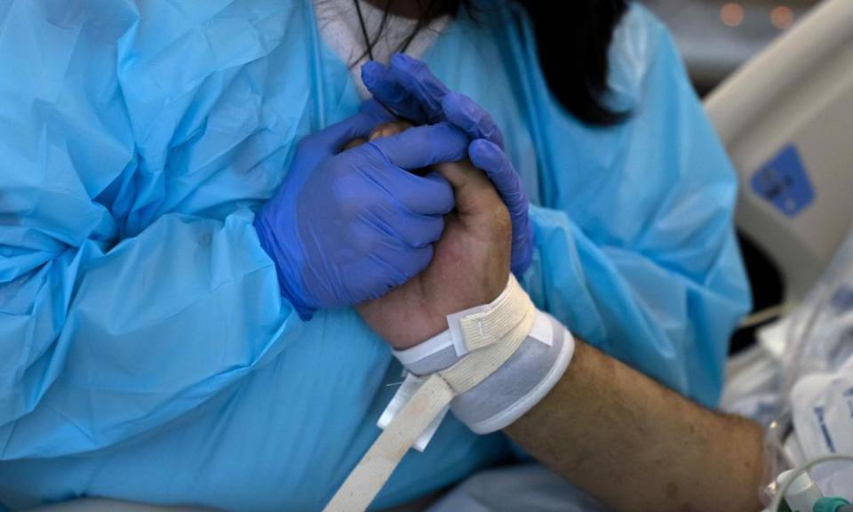 Patty Trejo, 54, holds the hand of her intubated husband, Joseph, in a Covid-19 unit at St Jude Medical Center in Fullerton, California.