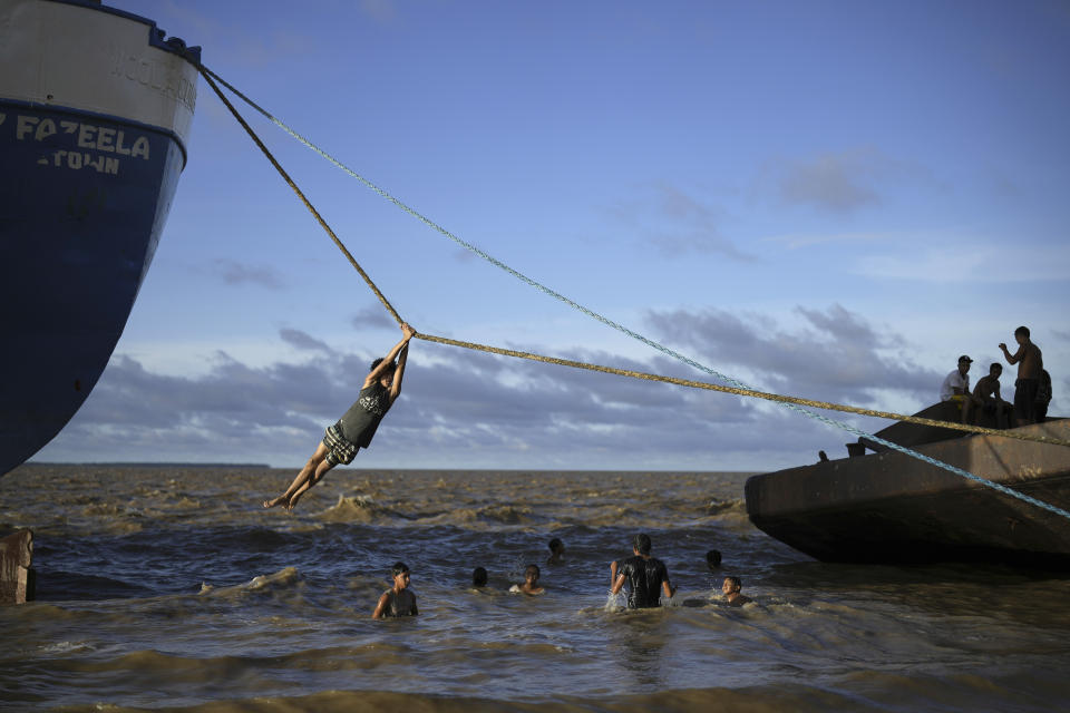Un niño desciende en rappel sobre un tramo del río Esequibo valiéndose de una cuerda de un buque anclado, el 9 de junio de 2024, en Parika, Guyana. (AP Foto/Ramón Espinosa)