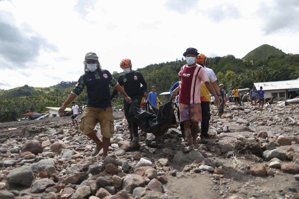 Rescuers carry a body which they retrieved after Tropical Storm Nalgae hit Maguindanao's Datu Odin Sinsuat town, southern Philippines on Saturday Oct. 29, 2022. Flash floods and landslides set off by torrential rains left dozens of people dead, including in a hard-hit southern Philippine province, where many villagers are feared missing and buried in a deluge of rainwater, mud, rocks and trees, officials said Saturday. (AP Photo)