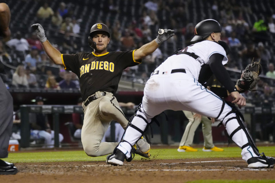 San Diego Padres' Adam Frazier, left, scores a run behind Arizona Diamondbacks catcher Carson Kelly on a ball hit by Jurickson Profar in the sixth inning during a baseball game, Tuesday, Aug. 31, 2021, in Phoenix. (AP Photo/Rick Scuteri)