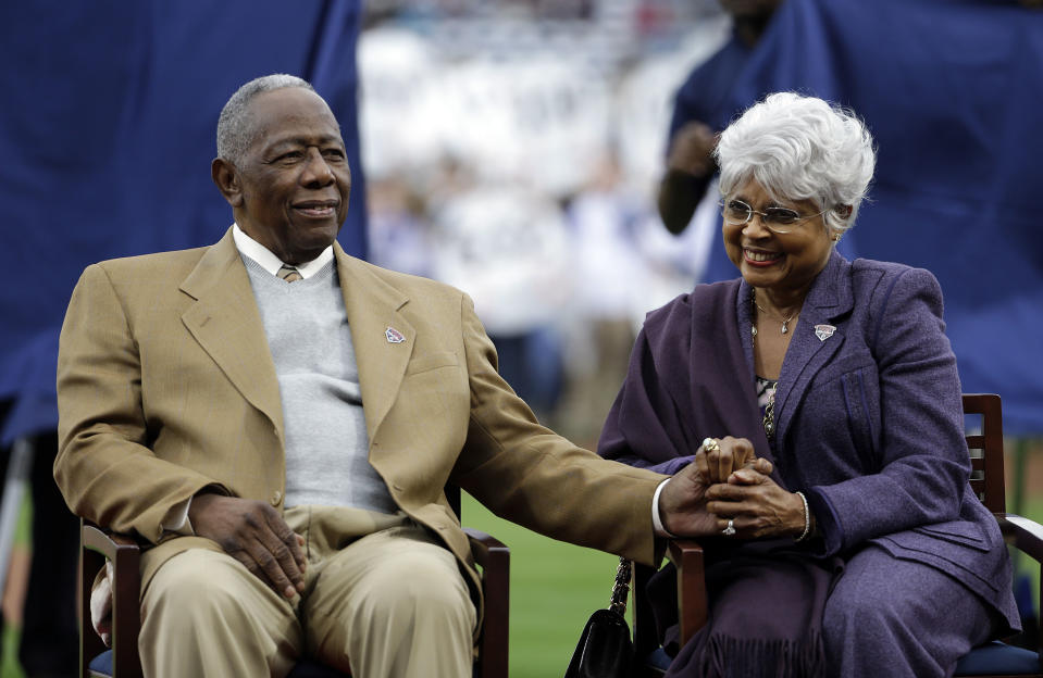 FILE - In this April 8, 2014, file photo, Hank Aaron, left, sits with his wife Billye, during a ceremony celebrating the 40th anniversary of his 715th home run before the start of a baseball game between the Atlanta Braves and the New York Mets in Atlanta. Hank Aaron, who endured racist threats with stoic dignity during his pursuit of Babe Ruth but went on to break the career home run record in the pre-steroids era, died early Friday, Jan. 22, 2021. He was 86. The Atlanta Braves said Aaron died peacefully in his sleep. No cause of death was given. (AP Photo/David Goldman, File)