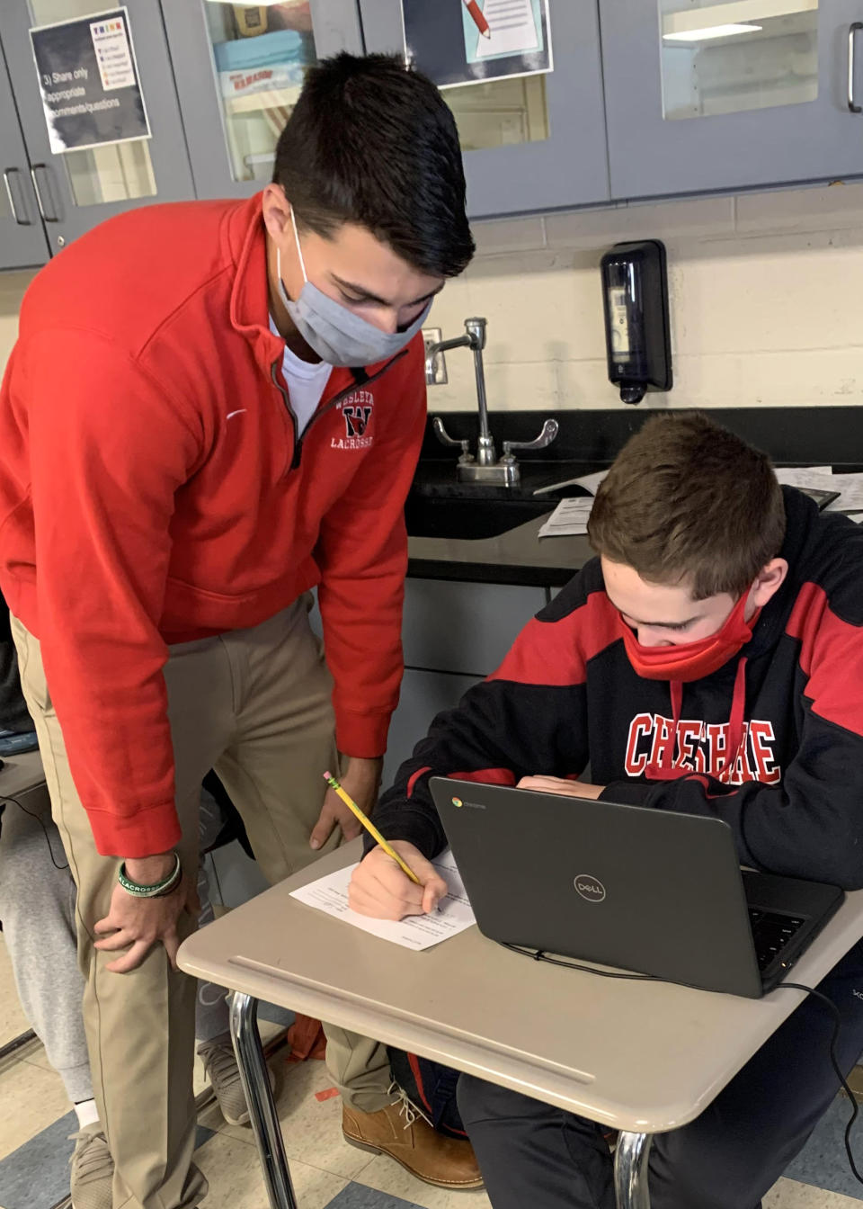 IMage: Jack Raba, a recent Cheshire Public Schools graduate, works with seventh grader Cody Persico at Dodd Middle School. Raba is one of about 50 graduates who answered the superintendent's appeal to help out by substitute teaching during the pandemic. (Courtesy of Cheshire Public Schools)