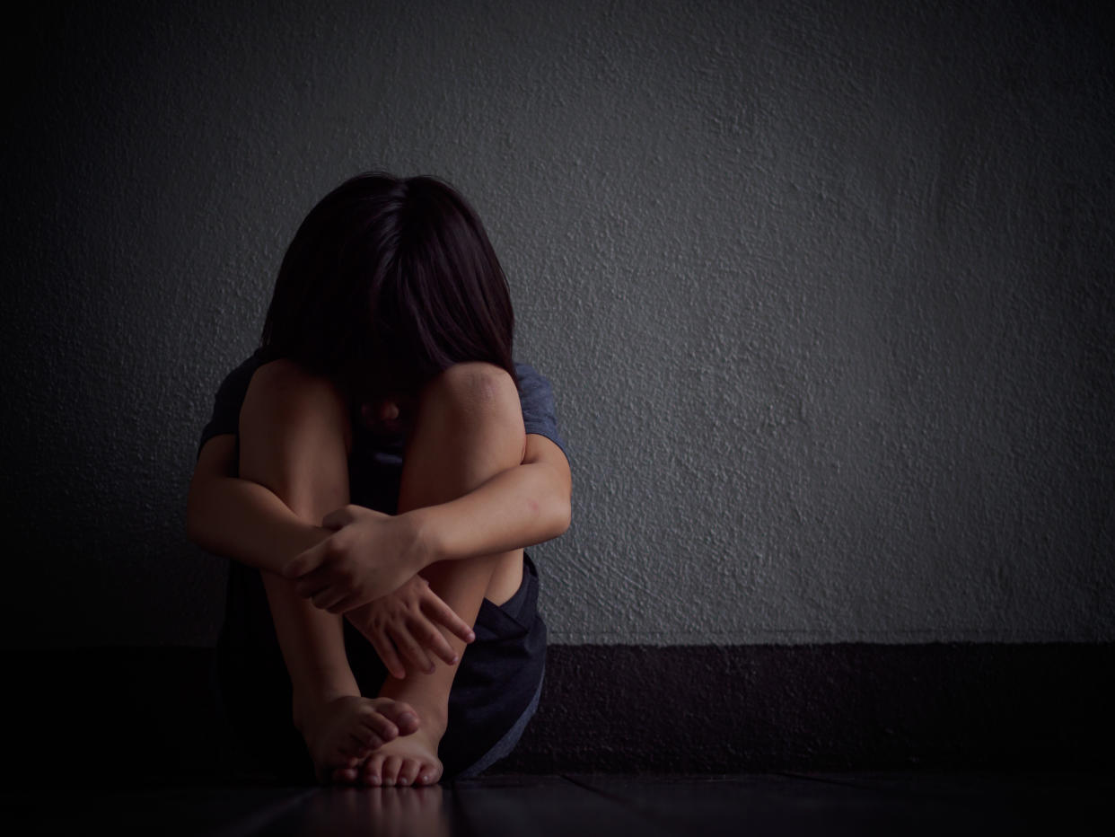 A child crouched before a wall. 