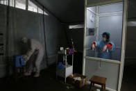 Nhuja Kaiju, left, of the RNA-16 volunteer group wearing protective suit helps a nurse collect swab samples of patients at a hospital in Bhaktapur, Nepal, Tuesday, May 26, 2020. RNA-16 stands for “Rescue and Awareness” and the 16 kinds of disasters they have prepared to deal with, from Nepal’s devastating 2015 earthquake to road accidents. But the unique services of this group of three men and a woman in signature blue vests in the epidemic amount to a much greater sacrifice, said doctors, hospital officials and civic leaders. (AP Photo/Niranjan Shrestha)