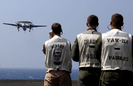 Flight deck crew watch as a U.S. Navy E2C Hawkeye lands on the deck of aircraft carrier USS Carl Vinson. REUTERS/Erik De Castro