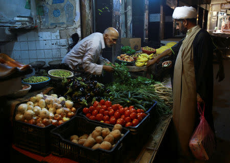 A Shi'ite cleric buys vegetables at a market in Najaf, south of Baghdad, Iraq, August 13, 2017. REUTERS/Abdullah Dhiaa Al-deen