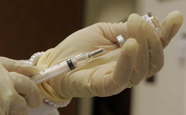 A nurse at the Travel and Adult Immunization Clinic in Pasadena fills a syringe, right, with flu vaccine.