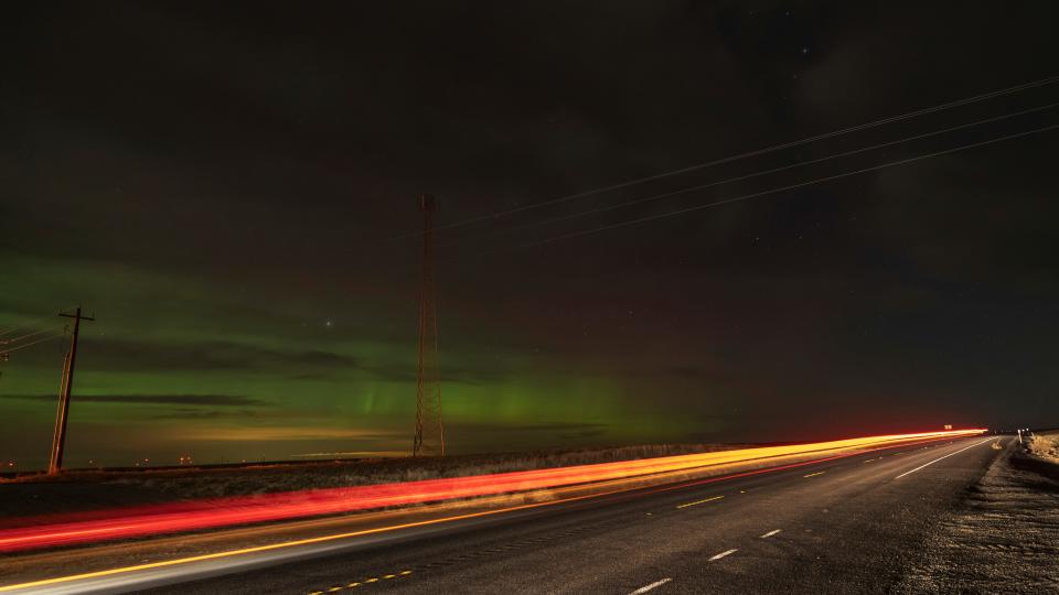 Lights from a passing vehicle on State Route 26 are tracked in this timed camera exposure as an aurora borealis, also known as the northern lights, is seen in the night sky on Sunday, Feb. 26, 2023, near Washtucna, Wash.