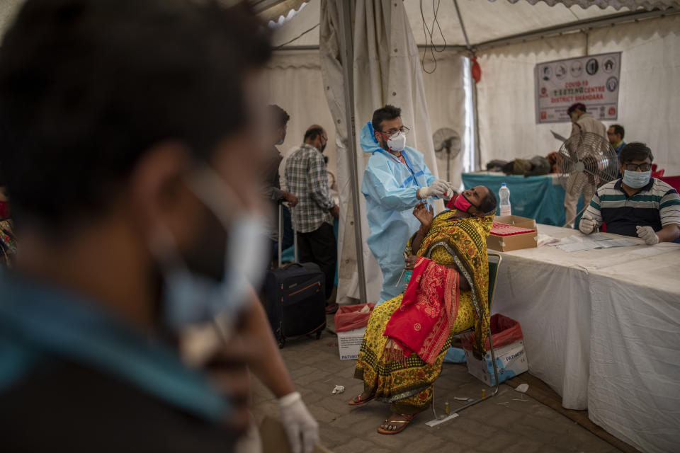 A health worker takes a nasal swab sample of a passenger to test for COVID-19 at a bus terminal in New Delhi, India, Wednesday, March 24, 2021. (AP Photo/Altaf Qadri)