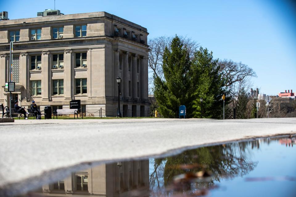 People sit on benches at a bus stop outside Macbride and Jessup Halls in this photo from 2020.