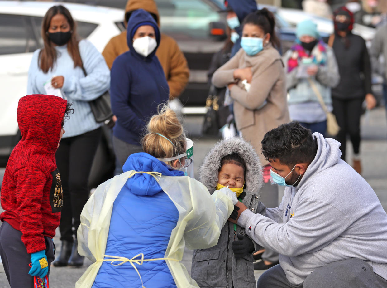 A man helps his son get a coronavirus test. Certain schools have begun pilot programs to offer rapid tests to students. (Photo by David L. Ryan/The Boston Globe via Getty Images)                                                                                                                                                          