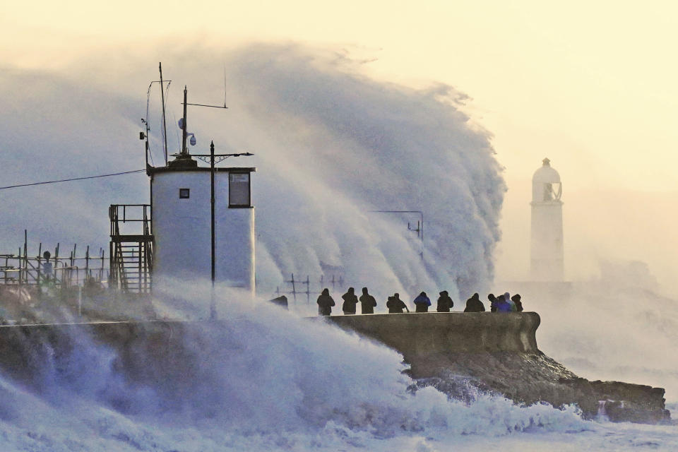 Waves crash against the sea wall and Porthcawl Lighthouse in Porthcawl, Bridgend, Wales,, Britain, as Storm Eunice makes landfall Friday, Feb. 18, 2022. Millions of Britons are being urged to cancel travel plans and stay indoors Friday amid fears of high winds and flying debris as the second major storm this week prompted a rare “red” weather warning across southern England. ( Jacob King/PA via AP)