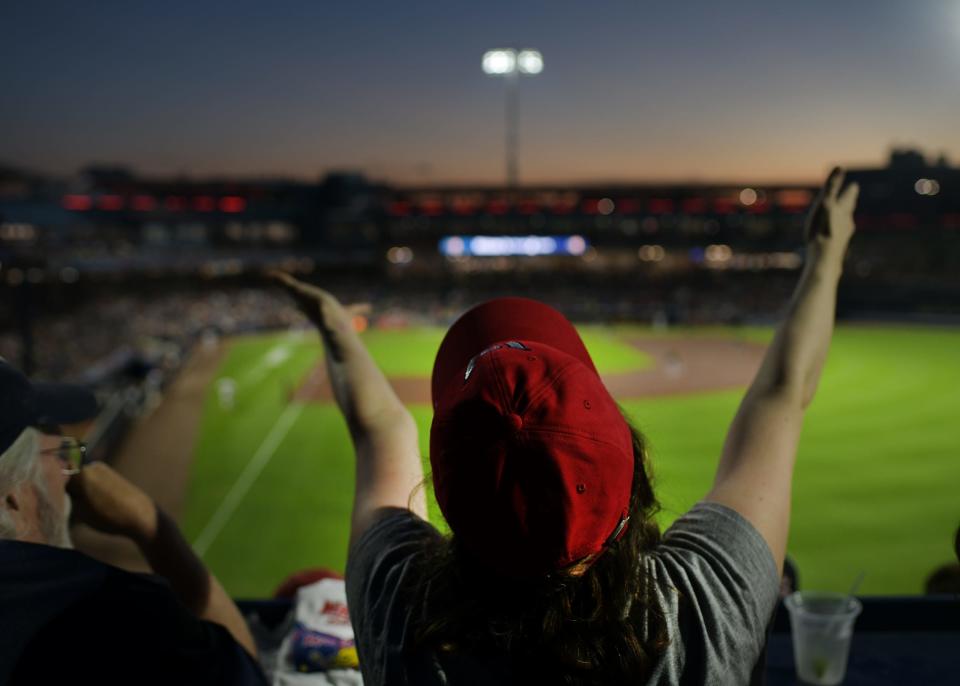 A woman raises her arms joyfully during “Sweet Caroline” a the WooSox game Friday.