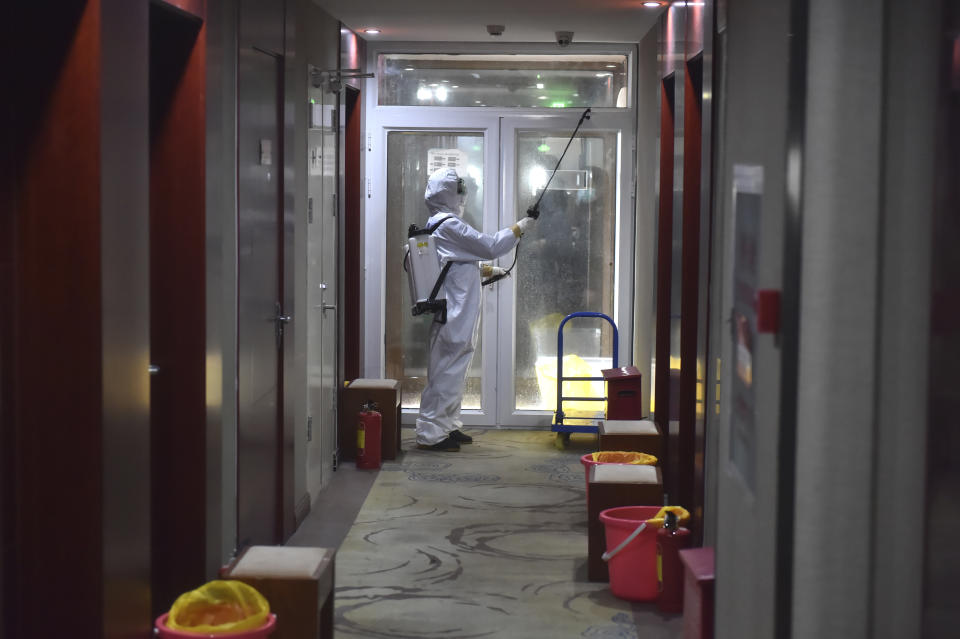 In this Feb. 21, 2020, photo released by China's Xinhua News Agency, a worker in a protective suit disintects a corridor of a hotel that has been converted to an observation and quarantine area for potential virus patients in Beijing. China's leadership sounded a cautious note Friday about the country's progress in halting the spread of the new virus that has now killed more than 2,200 people, after several days of upbeat messages. (Chen Zhonghao/Xinhua via AP)