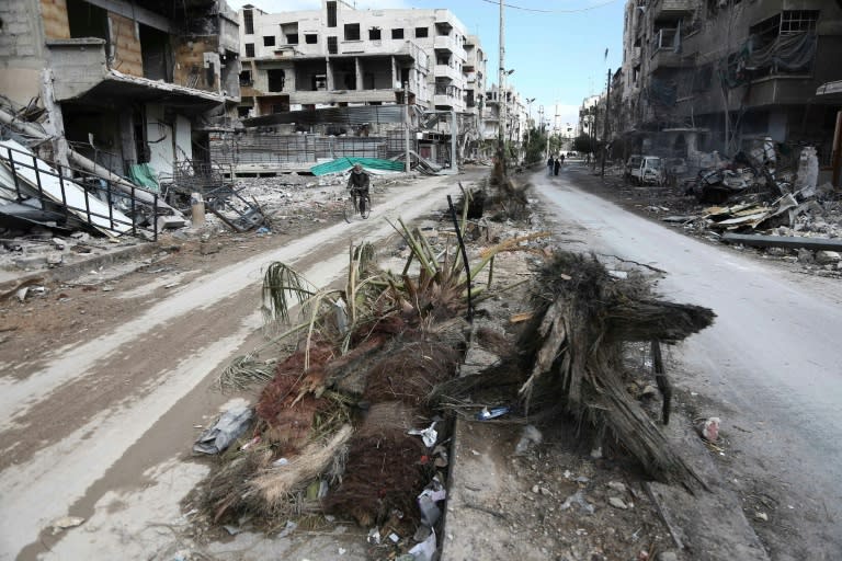 A Syrian man cycles past destroyed buildings in the rebel-held town of Hamouria, in the besieged Eastern Ghouta region on the outskirts of Damascus