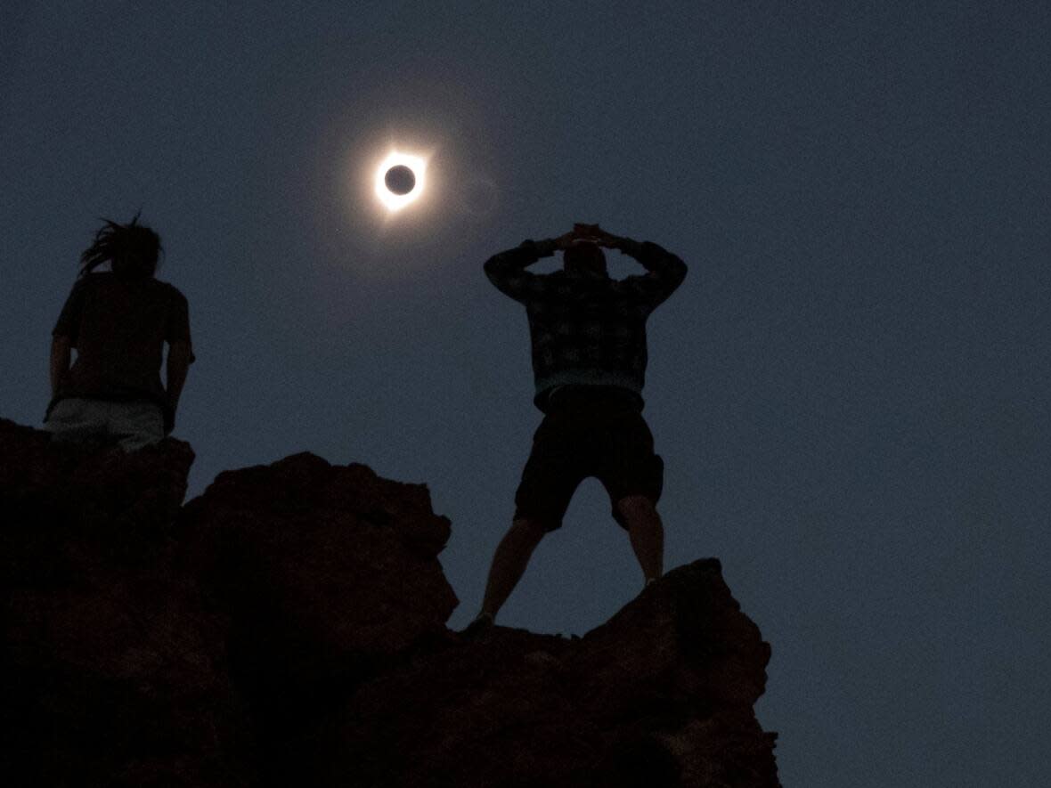 Two onlookers stand atop Carroll Rim Trail at Painted Hills, near Mitchell, Ore., during the total solar eclipse of 2017.   (Adrees Latif/Reuters - image credit)