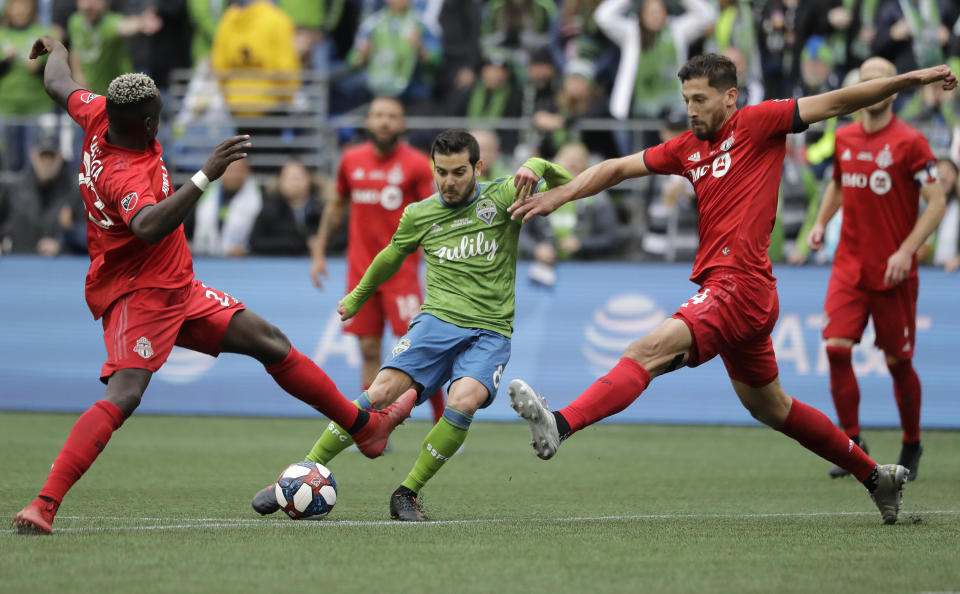 Seattle Sounders' Victor Rodriguez, center, kicks the ball to score between Toronto FC's Chris Mavinga, left, and Omar Gonzalez, Sunday, Nov. 10, 2019, during the second half of the MLS Cup championship soccer match in Seattle. (AP Photo/Ted S. Warren)