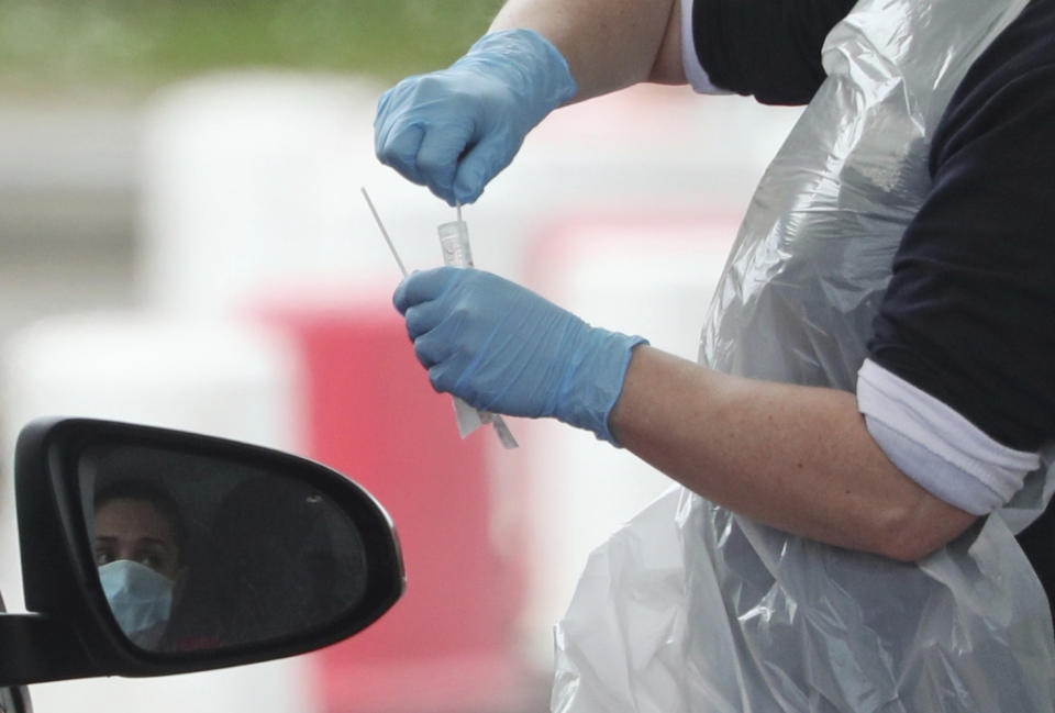 A NHS worker is tested at a drive through coronavirus testing site in a car park at Chessington World of Adventures, in Chessington, England, Wednesday April 1, 2020. (Yui Mok/PA via AP)