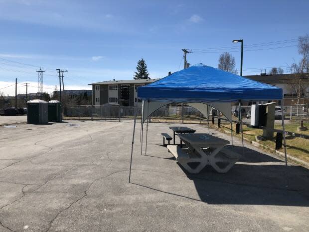 Picnic tables and portable toilets were set up in the parking lot next to Aspen Apartments on 51st Street after the temporary day shelter in downtown Yellowknife closed on Monday.  (Sidney Cohen/CBC  - image credit)