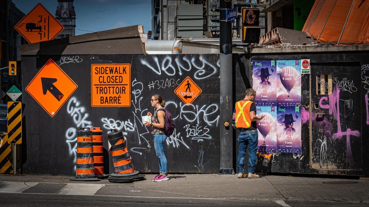 People stand around a crosswalk and construction site in downtown Ottawa in late August 2023. (Brian Morris/CBC - image credit)