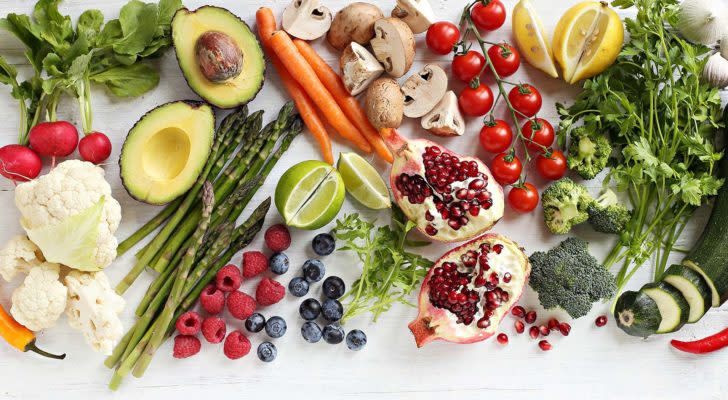 Vegetables and fruits are scattered over a white background.