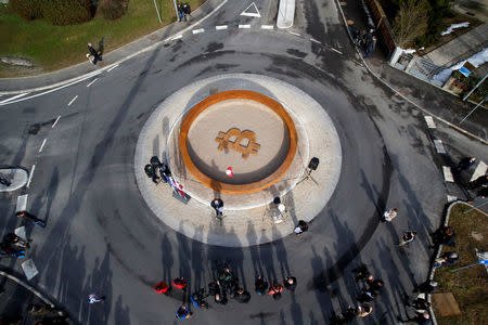 People attend the opening ceremony of world's first public Bitcoin monument, placed at a roundabout connecting two roads at the city centre in Kranj, Slovenia, March 13, 2018. REUTERS/Borut Zivulovic