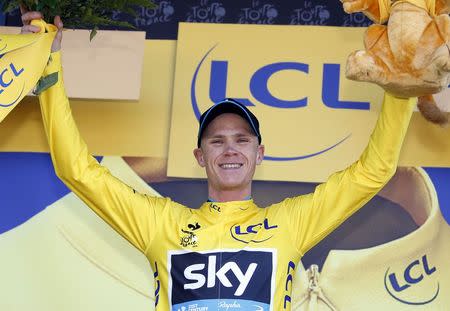 Team Sky rider Chris Froome of Britain celebrates as he wears the race leader's yellow jersey on the podium of the third stage of the 102nd Tour de France cycling race from Anvers to Huy, July 6, 2015. REUTERS/Eric Gaillard