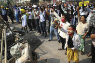 Protesters shout slogans behind the blockages they set up during a protest against the military coup in Yangon, Myanmar, Sunday, Feb. 28, 2021. Police fired tear gas and water cannons and there were reports of gunfire Sunday in Myanmar's largest city Yangon where another anti-coup protest was underway with scores of students and other demonstrators hauled away in police trucks. (AP Photo)